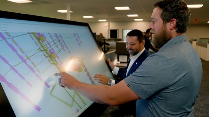 Two designers examining a building blueprint, collaborating on design and engineering solutions for a large construction project