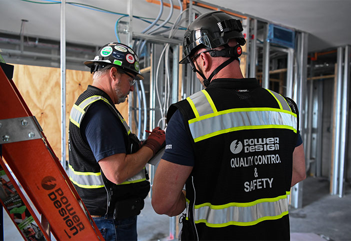 Two construction workers reviewing a clipboard to ensure compliance with quality and safety standards on a job site.